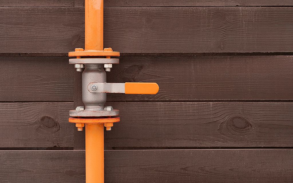 encanamento de metal na cor laranja sobre uma parede de madeira.